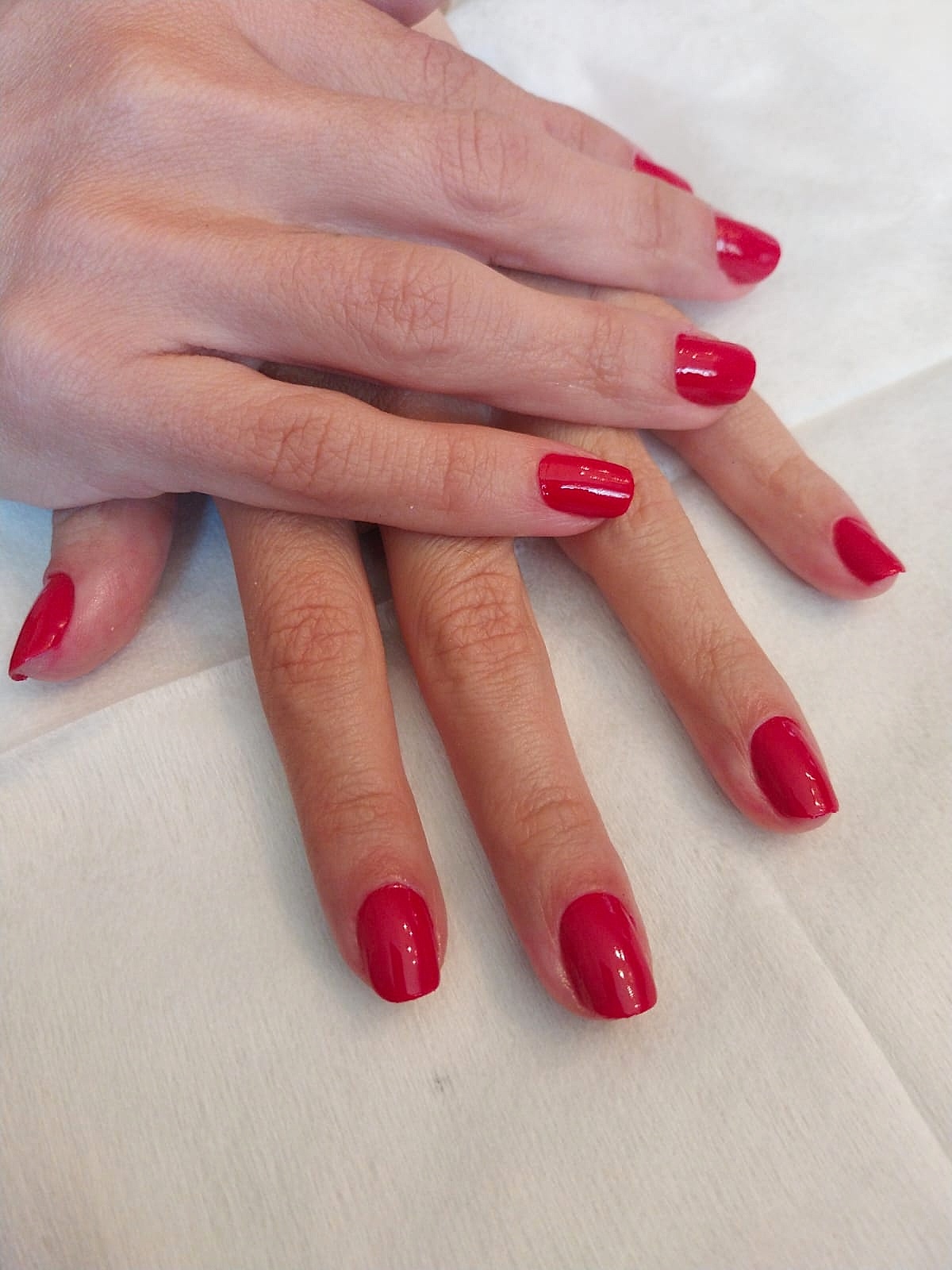 Manicure com esmalte vermelho feita pelo Espaço Luci